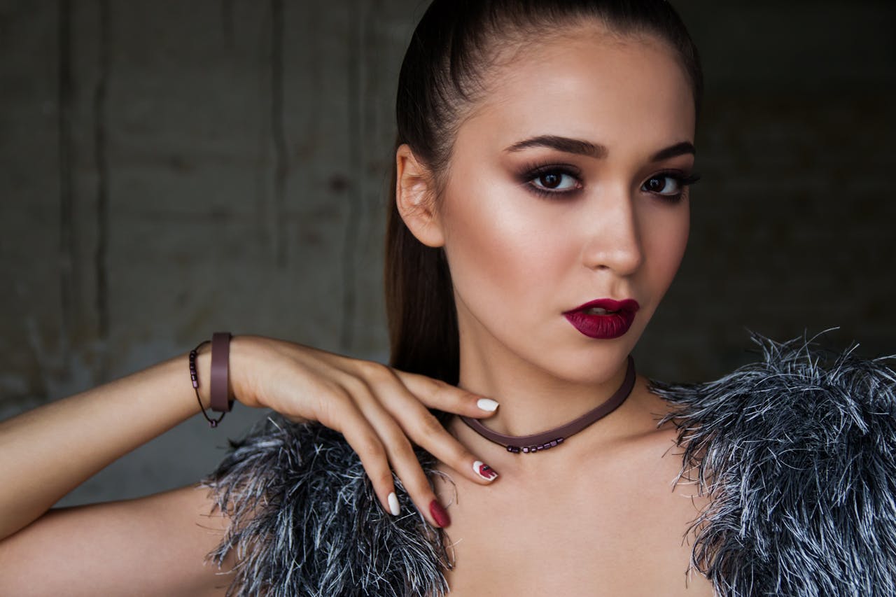 Close-up portrait of an elegant woman with bold makeup and fashionable attire, exuding confidence.